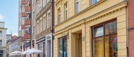 A street with buildings, outdoor seating, and a clear sky.