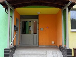Une entrée d’immeuble avec une porte à deux battants, un système d’alarme incendie et une petite fenêtre.