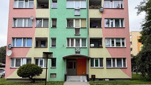 Ein mehrstöckiges Wohngebäude mit einem zentralen Eingang, Balkonen und Satellitenschüsseln.