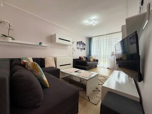 A modern living room with a sofa, coffee table, and a flat-screen TV.