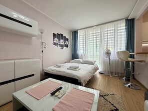 A modern hotel room with a bed, bedside table, lamp, and a view of the outdoors through sheer curtains. - Jelenia Góra Comfort Studio (Jelenia Góra)