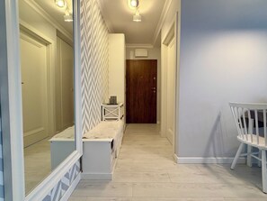 A hallway with a wooden door, a bench, and a white chair. - Kępa Mieszczańska Spacious Apartment (Wrocław)