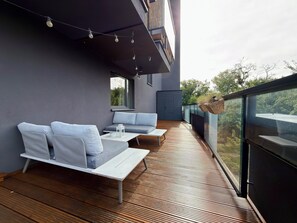Ein moderner Außenbereich mit Holzterrasse, grauen Sofas und einer hängenden Blumenampel.