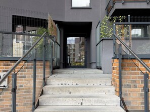 Eine Treppe führt zu einem Hauseingang mit Metallgeländern und einer Ziegelwand.