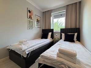 Habitación doble con dos camas, una ventana con cortinas y una obra de arte en la pared.