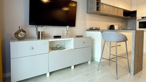 Uma cozinha moderna com forno embutido, um espaço de refeições com um banquinho de bar e uma TV de tela plana na parede.