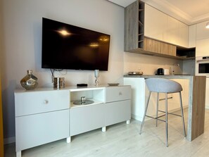 Eine moderne Küche mit Einbauofen, einer Essecke mit Barhocker und einem an der Wand befestigten Flachbildfernseher.