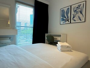 A hotel room with a bed, a desk, and two abstract paintings on the wall. - Kępa Mieszczańska Spacious Apartment (Wrocław)