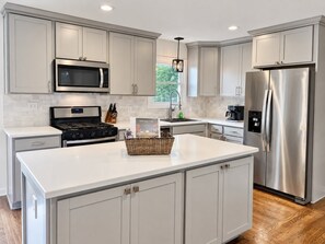 A modern kitchen with stainless steel appliances, a large island, and light-colored cabinetry. - Spacious 3BR Home Near Truist Park and I-75 (Marietta)