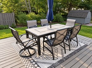 An outdoor patio with a table and chairs, surrounded by a wooden deck and a patterned rug. - Spacious 3BR Home Near Truist Park and I-75 (Marietta)