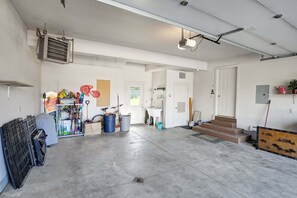 Eine geräumige Garage mit Betonboden, einem Fahrrad, einem Warmwasserbereiter und verschiedenen Aufbewahrungsbehältern.