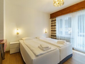 Ein Hotelzimmer mit einem Doppelbett, Nachttischen, einer Lampe und einem großen Fenster mit Vorhängen.