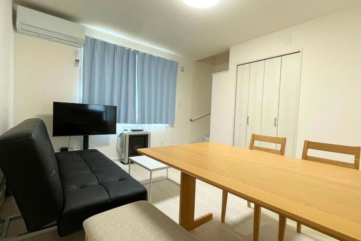 A room with a sofa, a TV, a table, and a wardrobe.