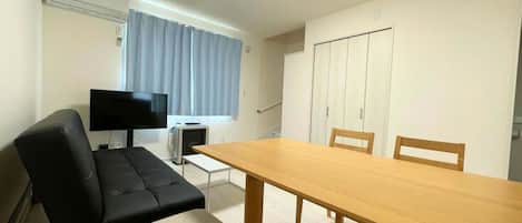Una habitación con sofá, televisión, mesa y armario.