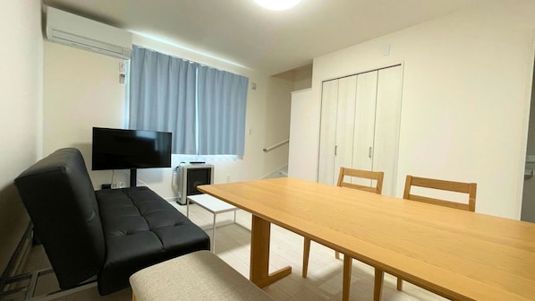Una habitación con sofá, televisión, mesa y armario.