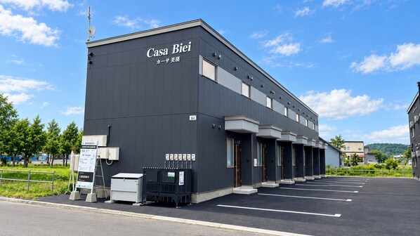 A modern building with a sign reading 'Casa Biei' and a parking lot in front.