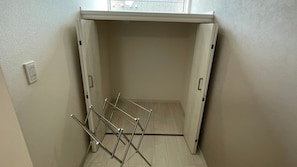 Una habitación pequeña y vacía con un tendedero metálico apoyado contra la pared.