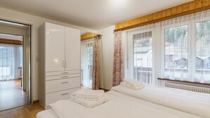 Ett hotellrum med två sängar, en garderob och stora fönster med gardiner.