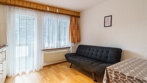 Ett rum med en soffa, ett element och ett fönster med gardiner.
