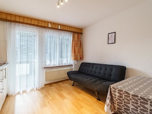 Ein Zimmer mit einer Couch, einem Heizkörper und einem Fenster mit Vorhängen.