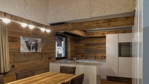 Eine rustikale Küche mit Holzwänden, einer zentralen Kochinsel und einem Essbereich mit Stühlen.