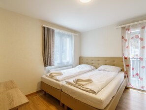 Ein Hotelzimmer mit Doppelbett, einem Vorhangfenster, einem Nachttisch und Holzboden.