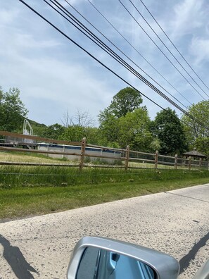 A paved road with a metal guardrail, a wooden fence, and a gazebo in the background. - Fantastic 3-bedroom house with AC in charming Walnutport (Walnutport)