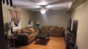 Ein Wohnzimmer mit zwei Sofas, einem Couchtisch, einer Lampe und einem Deckenventilator.