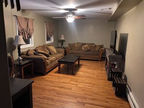 Ein Wohnzimmer mit zwei Sofas, einem Couchtisch, einer Lampe und einem Deckenventilator.