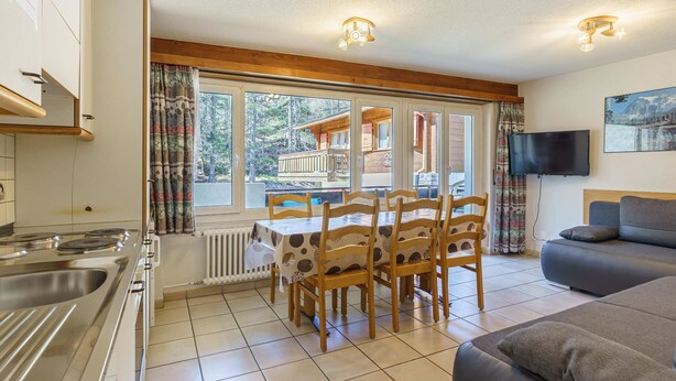 A modern kitchen with a dining area, a sofa, and a TV. - Haus Alfa by Interhome (Saas-Fee)
