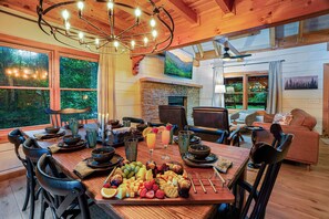 Un coin repas avec une table en bois dressée pour le repas, entourée de chaises, et une cheminée en arrière-plan.