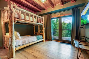 A cabin with a bunk bed, a wooden desk, and a large window with a view of greenery. - The Smoky Edit | 3 Decks | Hot Tub | Pool Table | 2 Fire Pits (Gatlinburg)