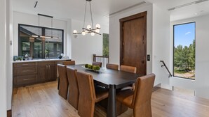 A modern dining area with a dark wooden table, leather chairs, and a unique chandelier. - Mountain-view Avon townhome with 3 bedrooms, hot tub, fireplace, and deck. (Avon)