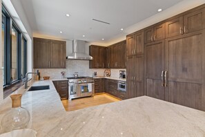Une cuisine moderne avec des meubles en bois foncé, des appareils électroménagers en acier inoxydable et un plan de travail en marbre.
