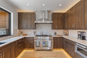 Eine moderne Küche mit Holzschränken, einem Edelstahlherd und einem Backofen.