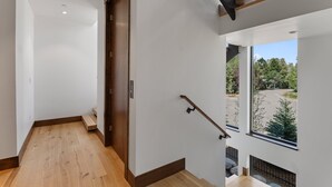 A modern interior with a wooden floor, a staircase, and a view of a parking area through a window. - Mountain-view Avon townhome with 3 bedrooms, hot tub, fireplace, and deck. (Avon)