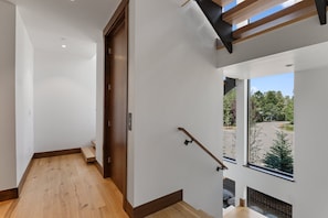 Ein modernes Interieur mit Holzboden, einer Treppe und Blick auf einen Parkplatz durch ein Fenster.