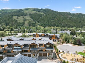 A modern resort with multiple-story buildings, a central courtyard, and a mountainous backdrop. - Mountain-view Avon townhome with 3 bedrooms, hot tub, fireplace, and deck. (Avon)