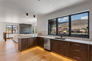 A modern kitchen with a large window, wooden cabinets, and a view of a hilly landscape. - Mountain-view Avon townhome with 3 bedrooms, hot tub, fireplace, and deck. (Avon)