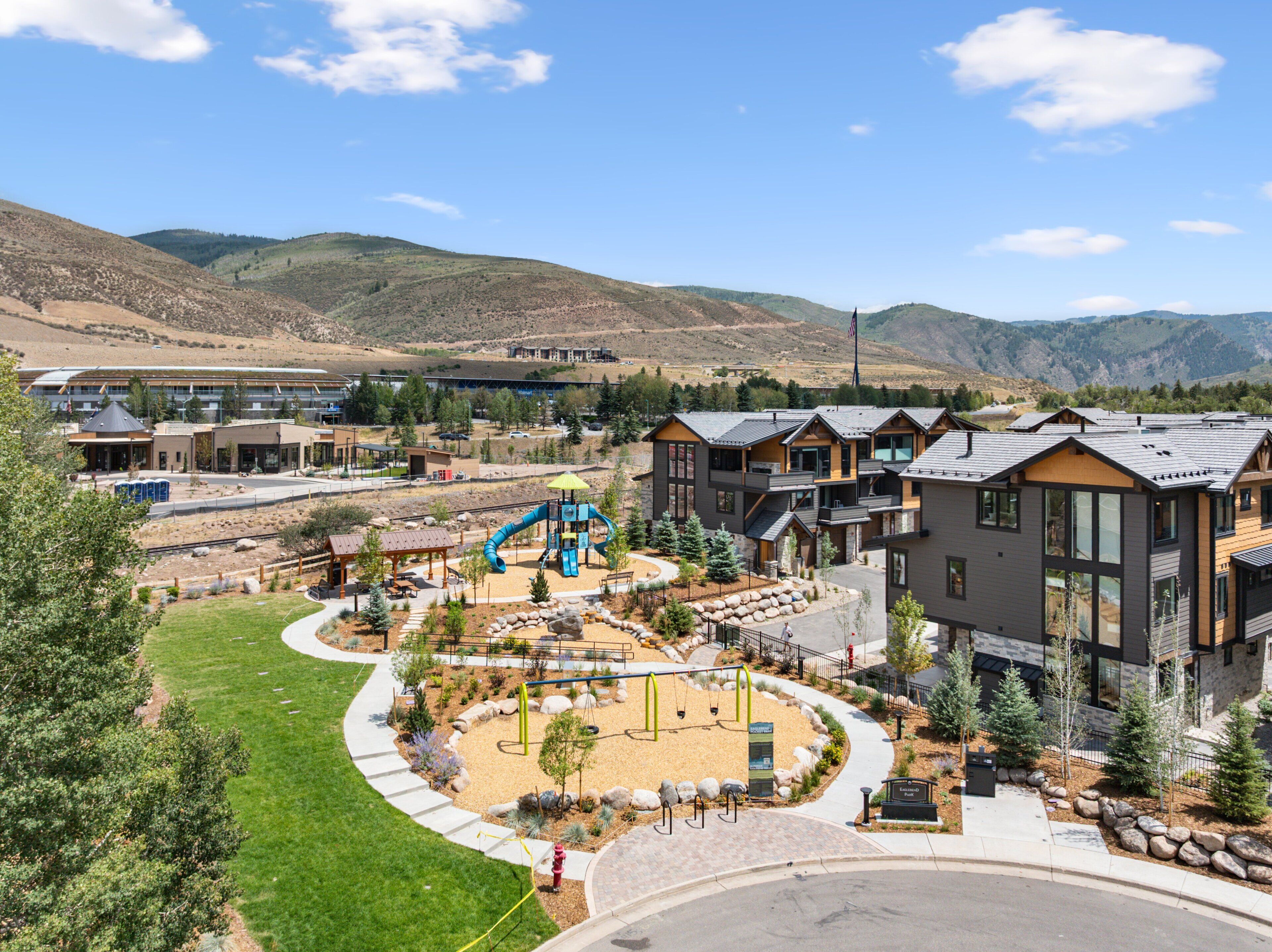 A residential area with modern houses, a playground, and a mountain backdrop.