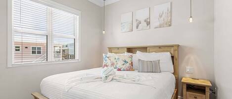 Un dormitorio con cama, mesita de noche, ventilador de techo y ventana con persianas.