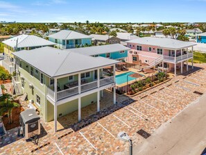 A coastal residential area with multiple two-story houses featuring balconies, a swimming pool, and a parking lot. - Poolside Fun, Pickleball & Coastal Adventures Await in Fort Myers - Jefferson Palms 123 - Roelens (Fort Myers Beach)