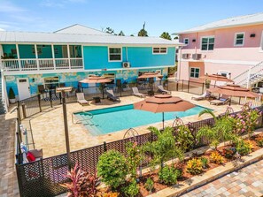 A hotel with a swimming pool, outdoor seating, and a fenced garden area. - Poolside Fun, Pickleball & Coastal Adventures Await in Fort Myers - Jefferson Palms 125-7a - Roelens (Fort Myers Beach)