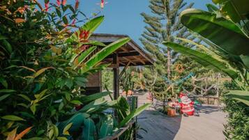 A wooden deck with a covered seating area, surrounded by lush tropical vegetation.