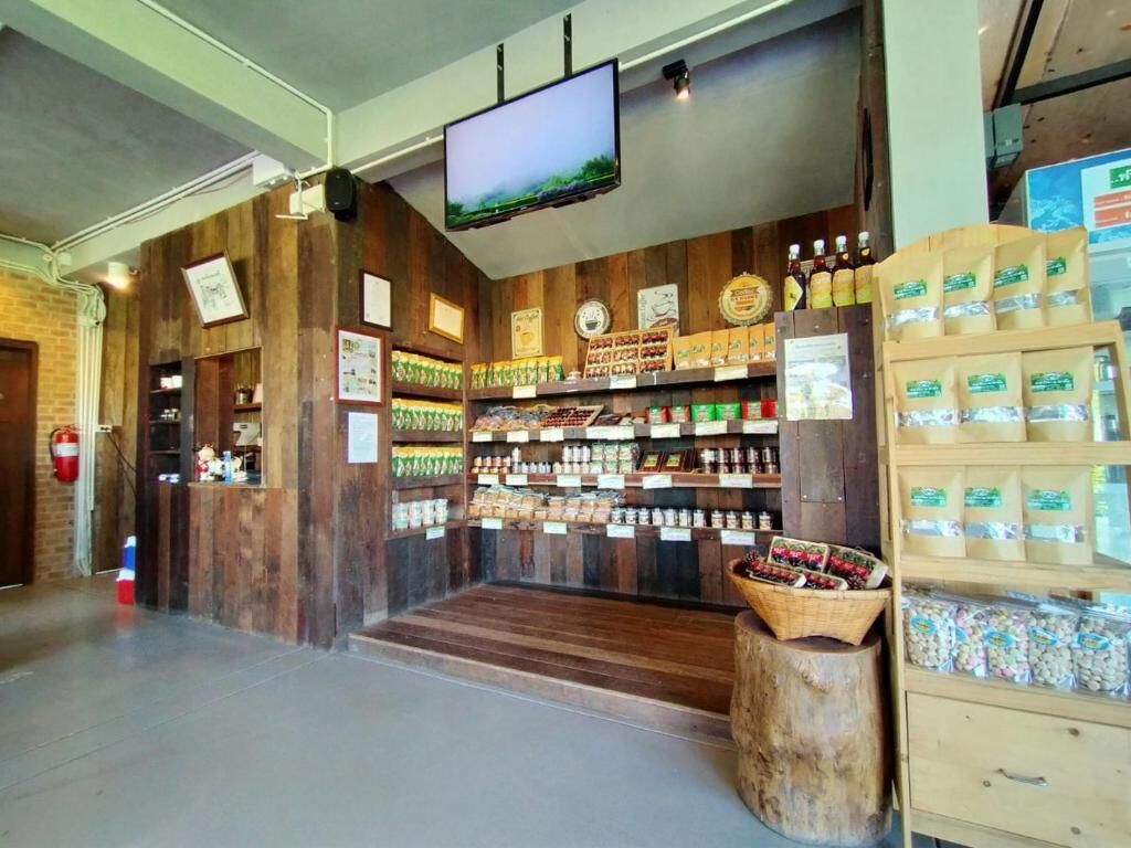 Interior de una tienda con paredes de madera, una pantalla de televisión y estantes llenos de diversos productos.