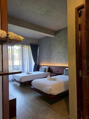 Habitación de hotel con dos camas, cabecero de madera y ventana con cortinas.