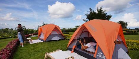 Two orange tents set up on a grassy field with a clear sky.