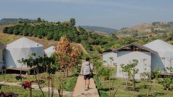 A pathway leading to a series of dome-shaped buildings surrounded by greenery and hills in the background.