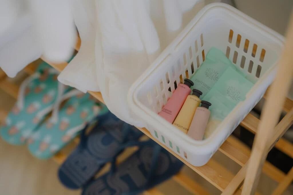 A white plastic basket containing toiletries on a wooden shelf.