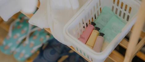 A white plastic basket containing toiletries on a wooden shelf.